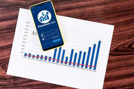 An overhead shot of a mobile phone with financial app and statistical graphs on screen