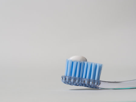A closeup shot of the head of a blue toothbrush with toothpaste in white backgroundの写真素材