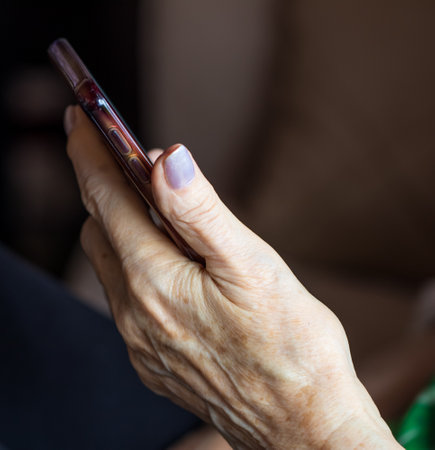 An elderly hand holding cellphoneの写真素材