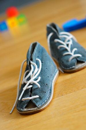 Pair of blie baby sandals on wooden floorの写真素材