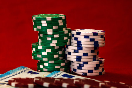 A closeup of piles of poker chips with Euro banknotes on a red table
