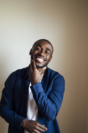 A vertical shot of a smiling black male in front of a brown background - happiness conceptの写真素材