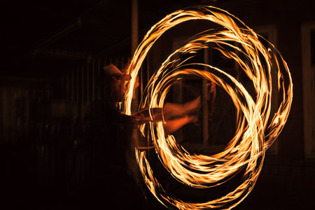 The spinning fire dancer performing burning fire poi danceの写真素材
