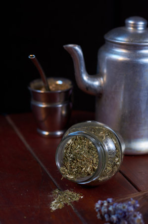 A vertical closeup shot of a traditional silver teapot, a cup, and herbal teaの写真素材