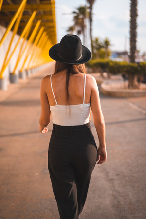 A beautiful brunette female in a black hat walking in a promenade in Torrevieja, Alicante, Spainの写真素材