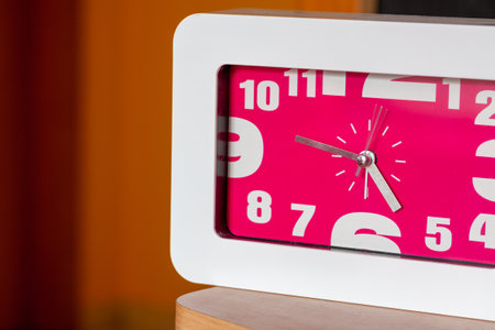 A closeup shot of a white watch with a pink dial