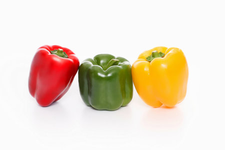 Three bell peppers of red, green, and yellow colors on a white backgroundの写真素材