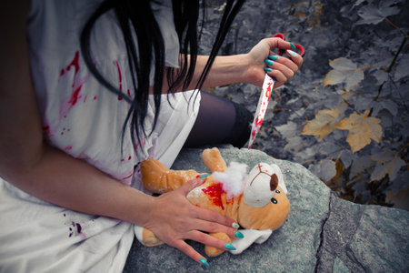 A crazy psycho girl stabbing a fluffy toy with a bloody knifeの写真素材