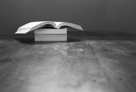 A black and white shot of books on a wooden tableの写真素材