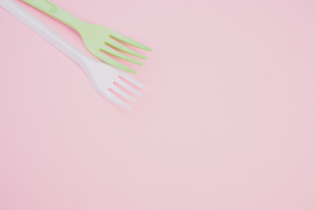 A closeup shot of plastic forks on a light pink backgroundの写真素材