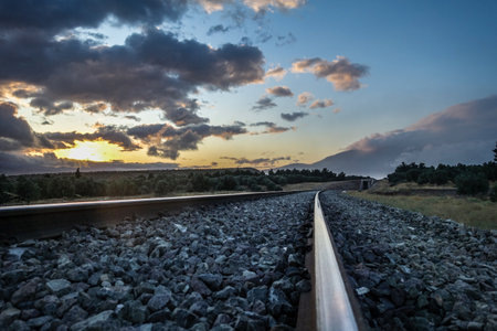 A mesmerizing view of the sunset with train rails and a beautiful cloudy skyの写真素材