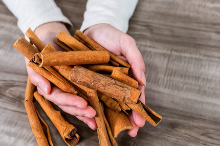 A top view of hands holding cinnamon sticksの写真素材