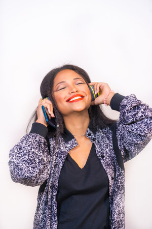 A vertical closeup of a young happy Hispanic female enjoying music with headphones