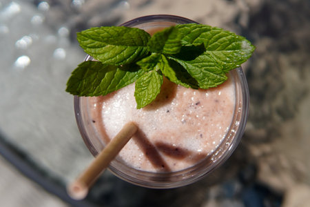 A top-view of a fresh milkshake with mint and an eco-friendly straw on a blurred backgroundの写真素材