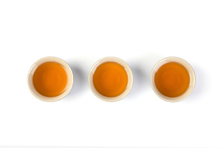 An overhead shot of poured black tea on three teacups isolated on white backgroundの写真素材