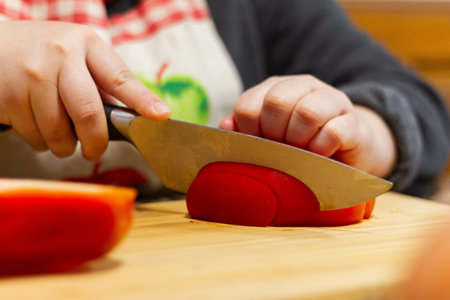 A soft focus of a cook slicing a red bell pepper on a wooden boardの写真素材