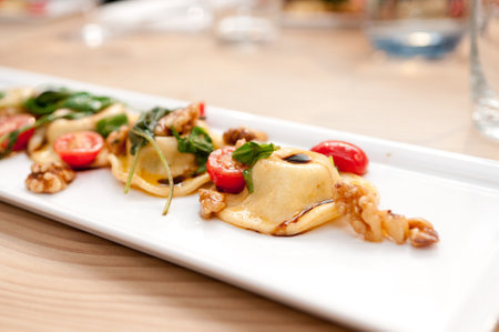 A closeup shot of dumplings decorated with tomatoes on a white plateの写真素材