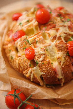 A vertical shot of a baked bread made with sauce and tomatoes on a blurred backgroundの写真素材
