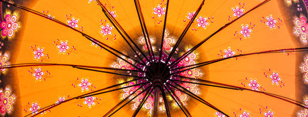 A low-angle shot of a yellow Japanese umbrella with flower patternsの写真素材
