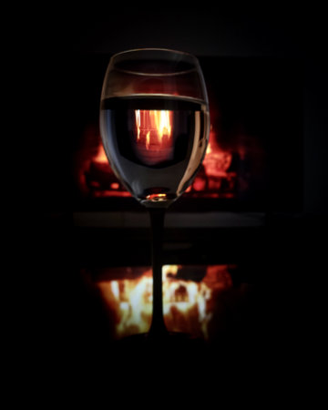 A cozy evening with a glass of wine by the fireplaceの写真素材