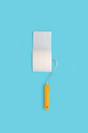 A vertical shot of a painting roller with toilet paper on a pastel blue backgroundの写真素材