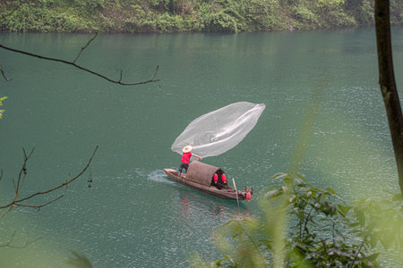 A high angle shot of a fisherman on a fishing boat captured in Hunan, Chinaの写真素材