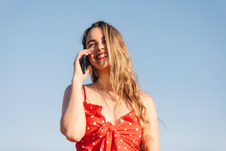A closeup shot of a young Caucasian female laughing and talking on the phoneの写真素材