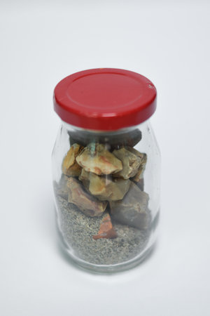 A vertical shot of stones and sand in the jar on an isolated backgroundの写真素材