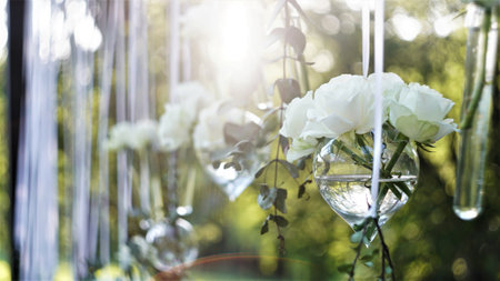 White roses hanging in a glass vase at an exterior venueの写真素材
