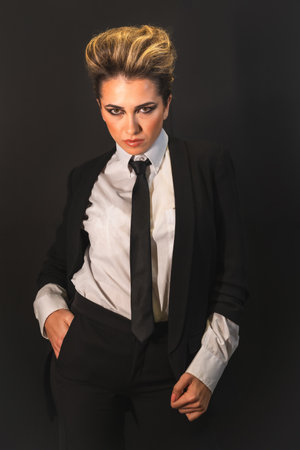 A sexy young blonde hair female in a black suit posing at cameraの写真素材