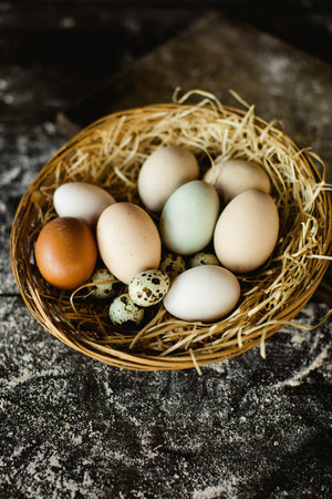 A vertical shot of fresh chicken and quail eggs in a basketの写真素材