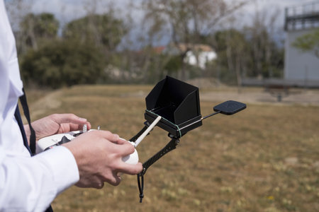 a closeup of the hands of a drone pilot with remote control, screen and wifi antenna starting the...