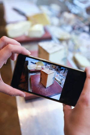 A vertical shot of a smartphone capturing a block of cheese in a local supermarketの写真素材