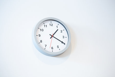 A low angle closeup view of a white clock on a white wallの写真素材