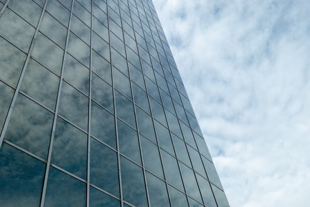A low angle shot of the reflection of the fluffy clouds on a modern building