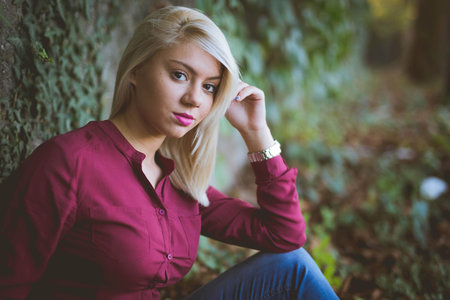 An attractive Bosnian Caucasian woman beside the leaves-covered wall