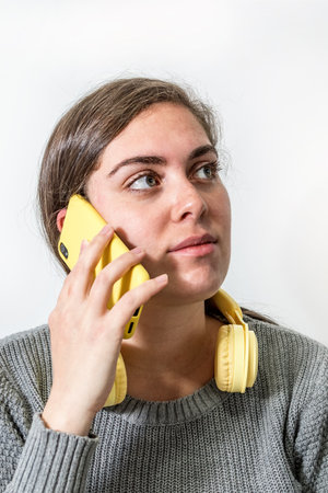 An attractive Israeli young woman talking on her smartphone with yellow wireless headset on her neckの写真素材