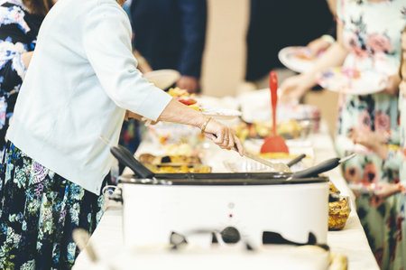 An aged female taking some food at a buffetの写真素材