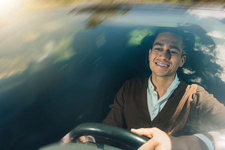 A Latin man happily smiling and driving a car
