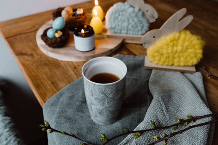 A closeup shot of lighting candles, a cup of espresso and cute decorative Easter eggs and bunniesの写真素材