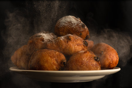 A plate of fresh oliebollens just out of the oven with baking powder over them