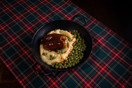 A top-view of glazed sausages with mashed potato and green beans served on a pan - vertical shotの写真素材