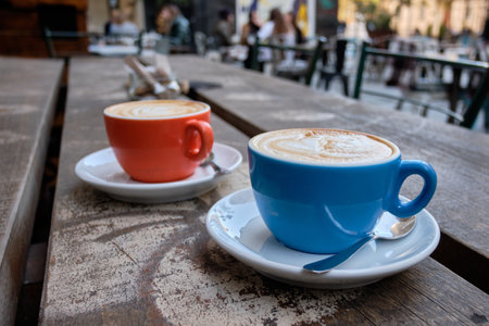 A closeup shot of two cups of latte coffee on a wooden surfaceの写真素材