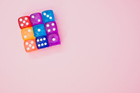 A cube made of colorful dice isolated on a pink backgroundの写真素材
