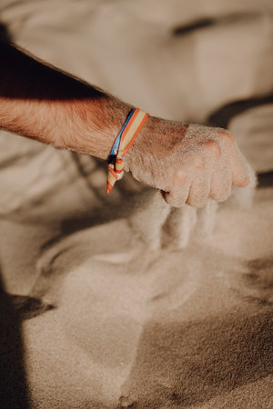 A vertical shot of a person playing with the sand at the beachの写真素材