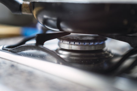 A closeup of a pan on a lit stove, in a kitchen indoorsの写真素材