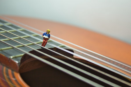 A closeup shot of a small figure of a person on a classical guitar