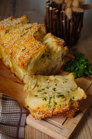 A vertical shot of homemade bread with herbs on a wooden cutting boardの写真素材