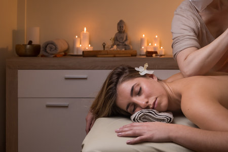 A feminine Spanish woman lying on a massage table receiving massage therapy in a wellness centerの写真素材