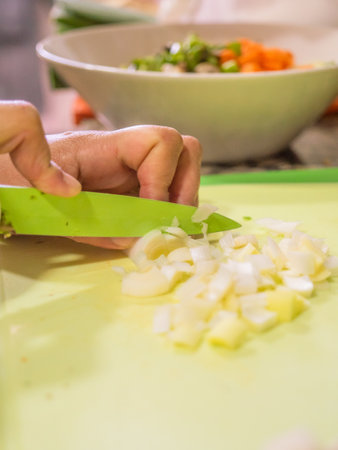 A vertical shot of a female's hands chopping leeks with a green knifeの写真素材